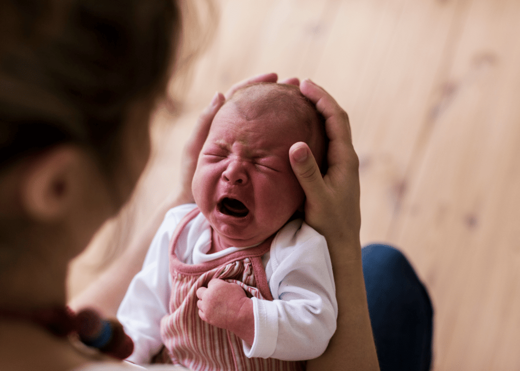 bébé pleure dans les bras de sa maman